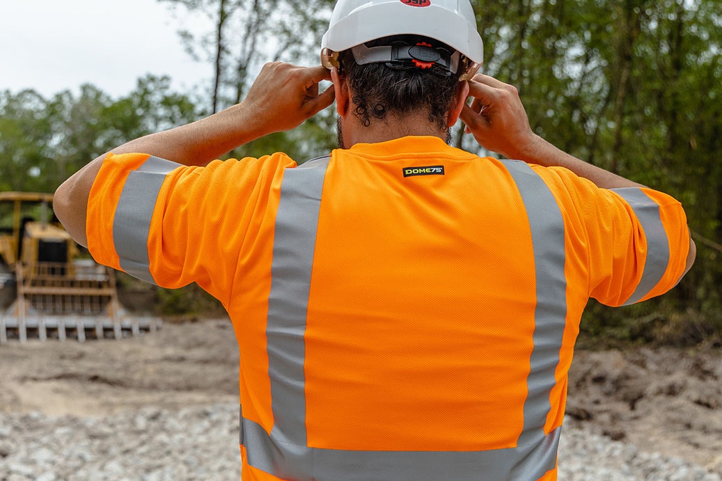 technician at construction site with an orange hi-vis shirt 